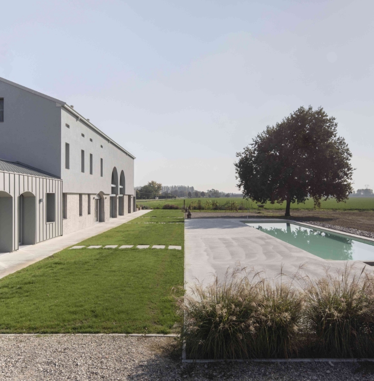 Cortile moderno con prato verde e pavimento in cemento a basso spessore Isoplam, piscina rettangolare e albero sullo sfondo, soluzione ideale per ristrutturazioni senza demolizioni